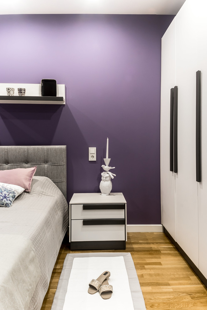 На фото: хозяйская спальня среднего размера в современном стиле с фиолетовыми стенами, паркетным полом среднего тона и бежевым полом