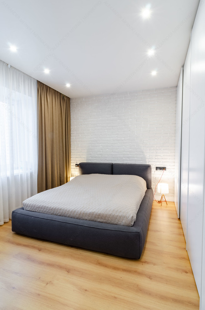 Diseño de dormitorio principal industrial pequeño sin chimenea con paredes blancas, suelo laminado y suelo beige