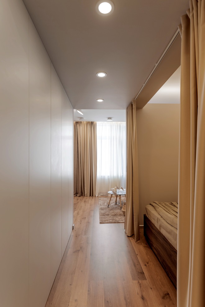 Foto de dormitorio principal actual de tamaño medio sin chimenea con paredes grises, suelo laminado y suelo marrón
