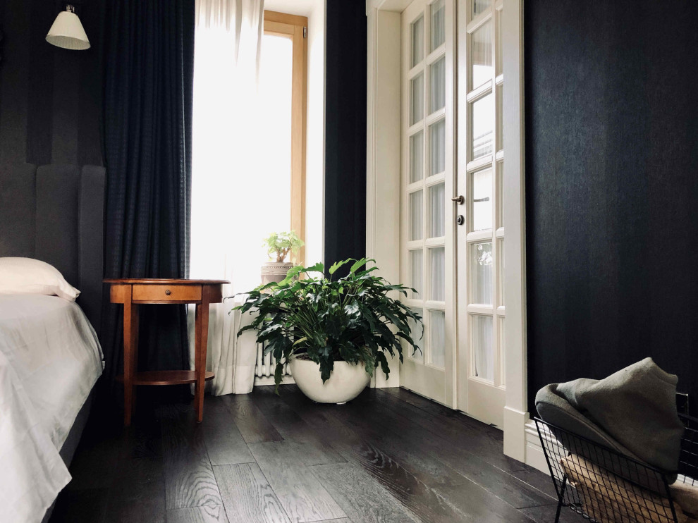 Ejemplo de dormitorio principal clásico renovado grande con paredes negras, suelo de madera oscura, chimenea de esquina, marco de chimenea de metal y suelo negro