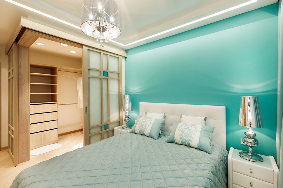 Réalisation d'une chambre parentale design de taille moyenne avec parquet clair, un mur bleu et un sol beige.