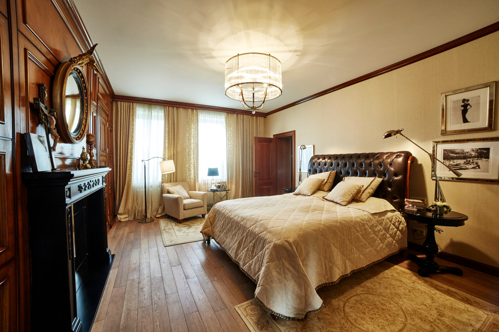 Foto di una camera matrimoniale chic di medie dimensioni con pareti beige, pavimento in legno massello medio e cornice del camino in legno