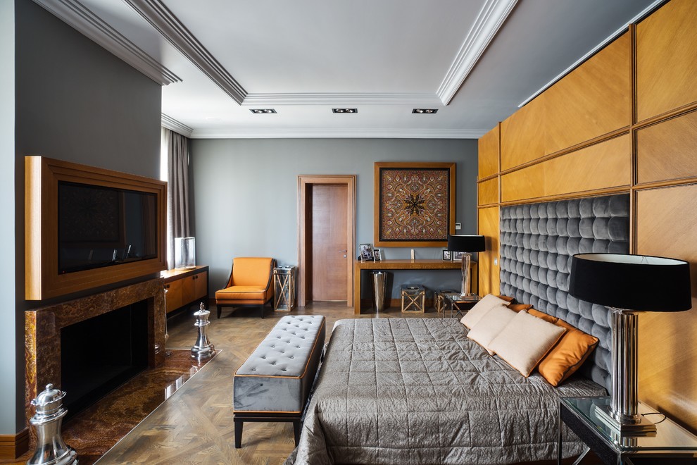 Foto de dormitorio clásico renovado con paredes grises, suelo de madera en tonos medios, todas las chimeneas, marco de chimenea de piedra y suelo marrón