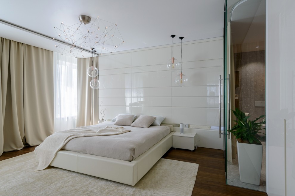 Cette image montre une chambre parentale design avec un mur blanc, un sol marron et parquet foncé.