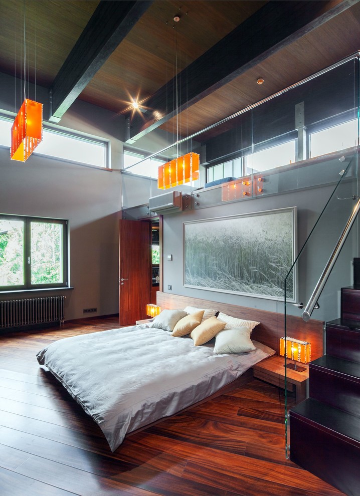 Inspiration pour une chambre design avec un mur gris, un sol en bois brun et aucune cheminée.