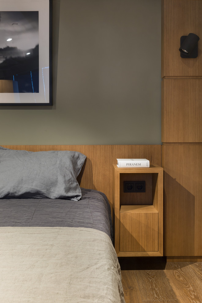 Ejemplo de dormitorio actual pequeño con paredes verdes, suelo de madera en tonos medios y suelo marrón