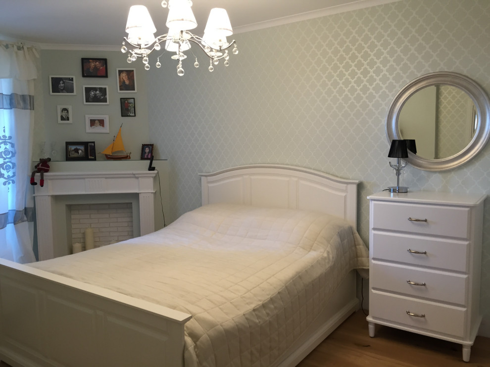На фото: хозяйская спальня среднего размера в стиле неоклассика (современная классика) с бежевыми стенами, полом из ламината, угловым камином, бежевым полом и обоями на стенах с