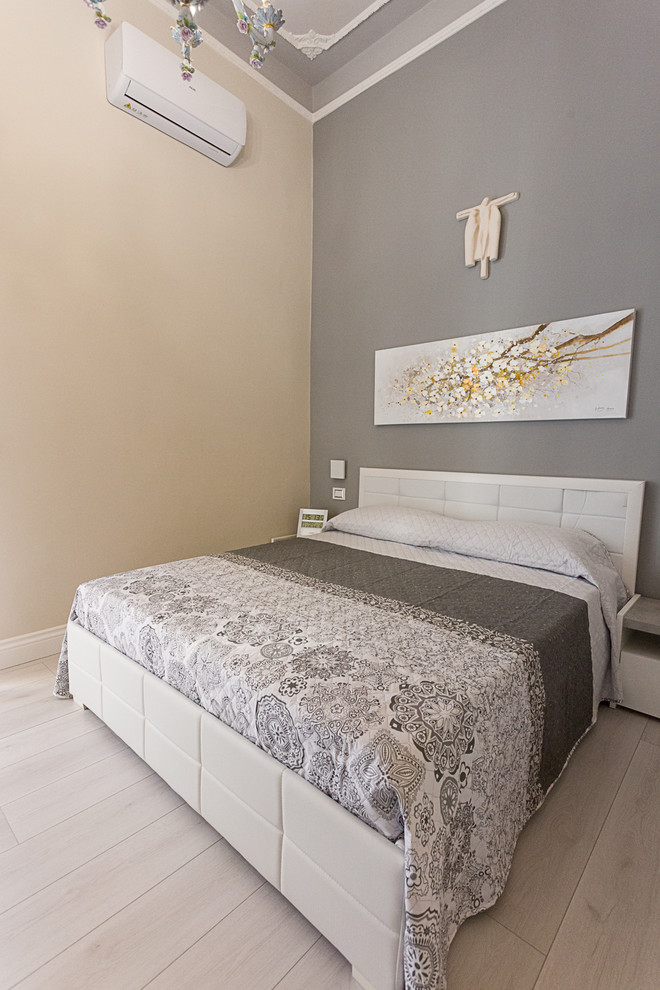 На фото: маленькая хозяйская спальня в современном стиле с серыми стенами, полом из ламината и серым полом для на участке и в саду