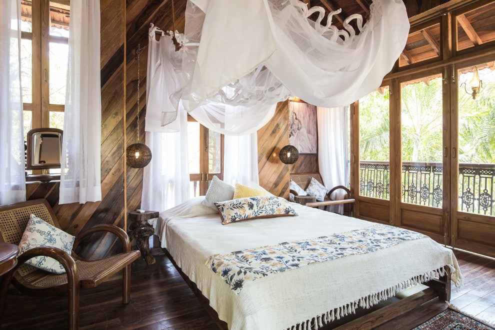 Immagine di una camera da letto tropicale con parquet scuro e pavimento marrone