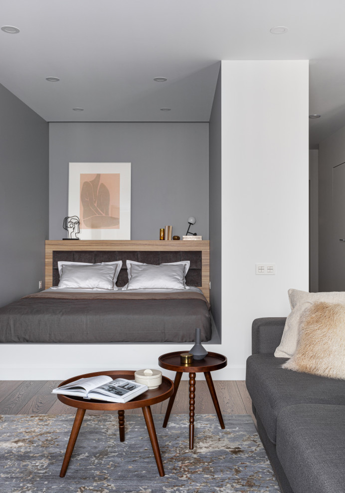 Modernes Schlafzimmer mit grauer Wandfarbe, braunem Holzboden und braunem Boden in Moskau