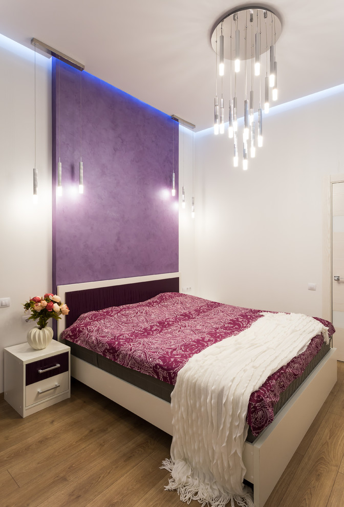 Diseño de dormitorio principal actual de tamaño medio con paredes blancas, suelo laminado y suelo beige