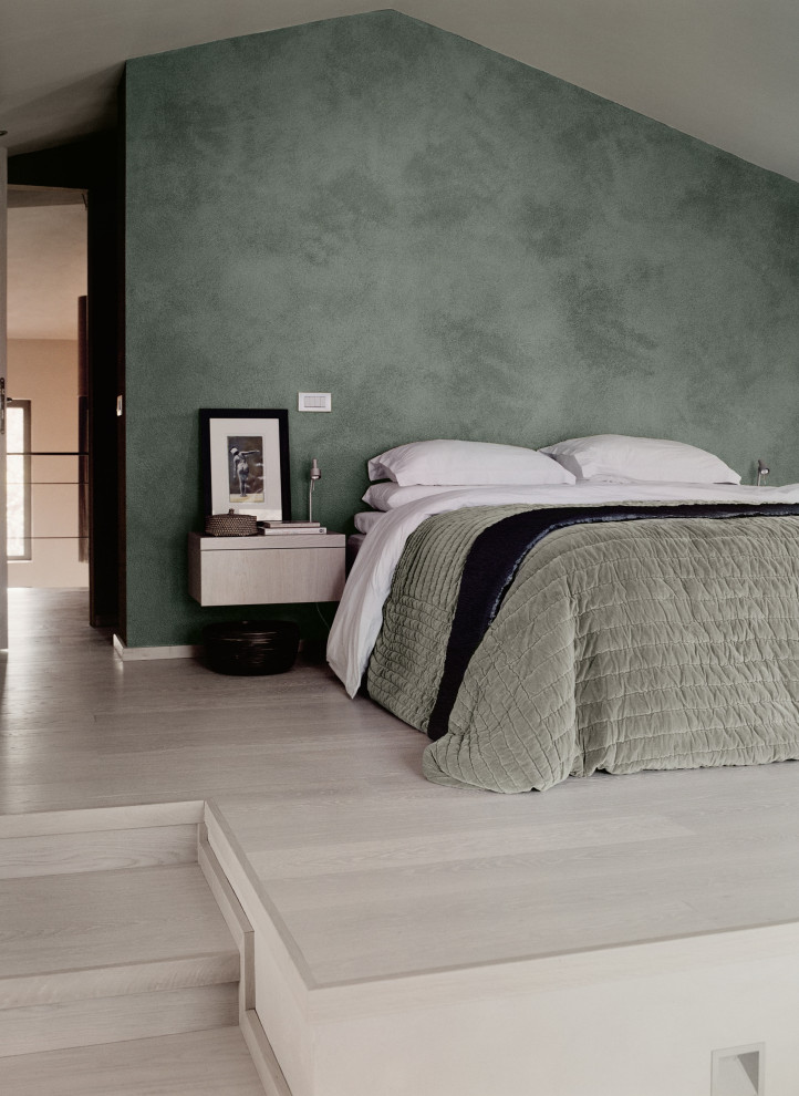 На фото: спальня в скандинавском стиле с зелеными стенами, полом из ламината и белым полом с