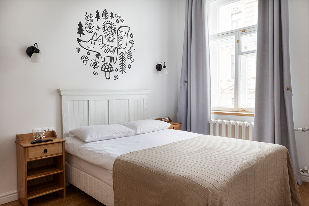 Ejemplo de dormitorio principal nórdico de tamaño medio con paredes blancas, suelo laminado y suelo marrón