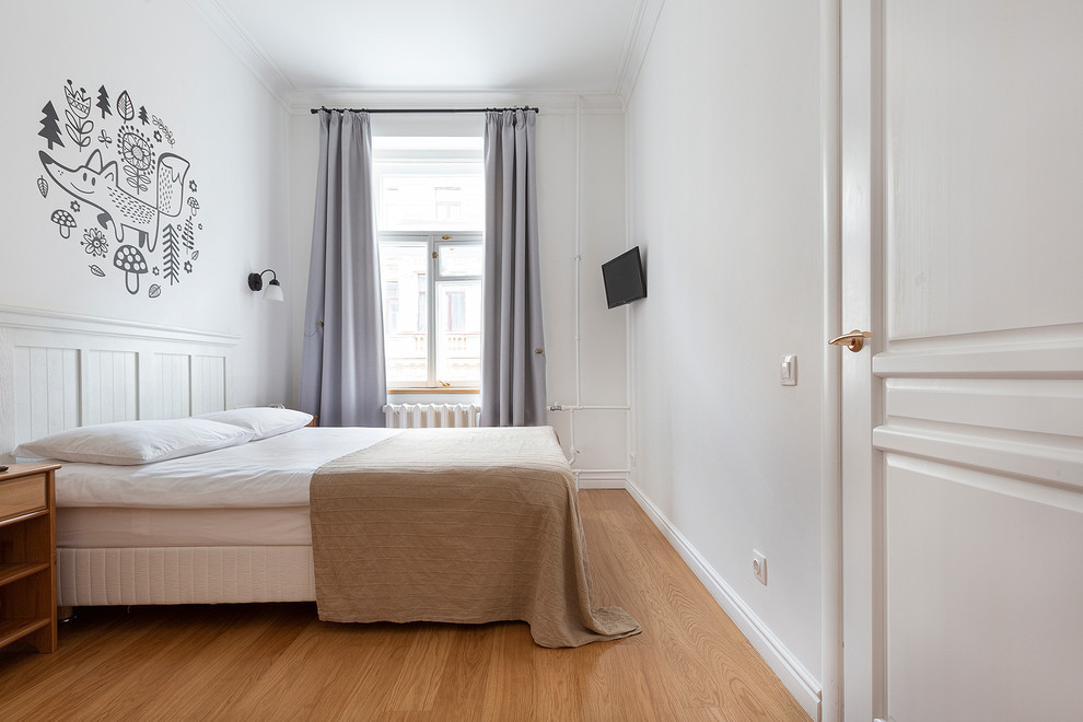 Immagine di una camera matrimoniale nordica di medie dimensioni con pareti bianche, pavimento in laminato e pavimento marrone
