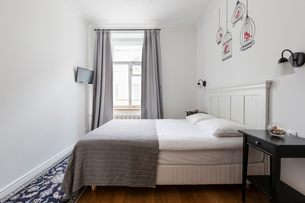 Ejemplo de dormitorio principal nórdico de tamaño medio con paredes blancas, suelo laminado y suelo marrón