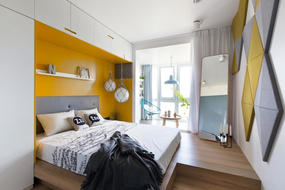 Immagine di una camera matrimoniale design con pareti gialle, pavimento in legno massello medio e pavimento marrone