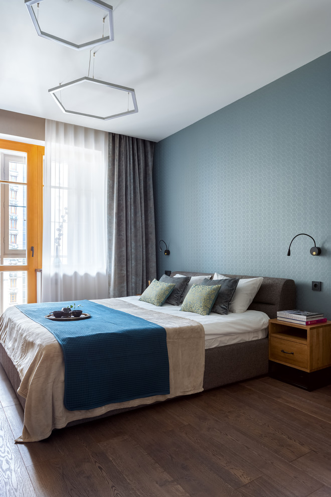 Aménagement d'une chambre parentale contemporaine de taille moyenne avec un mur bleu, un sol en bois brun et un sol marron.