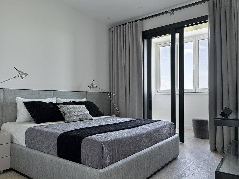 Modelo de dormitorio principal contemporáneo con paredes blancas, suelo de madera clara y suelo beige