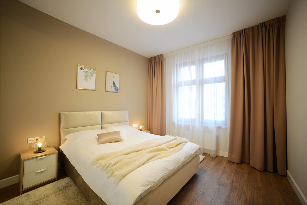 Idée de décoration pour une chambre parentale design de taille moyenne avec un mur beige, sol en stratifié et un sol marron.