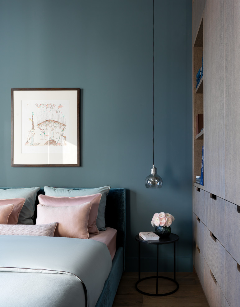Cette image montre une petite chambre design avec un mur bleu, un sol en bois brun et un sol marron.