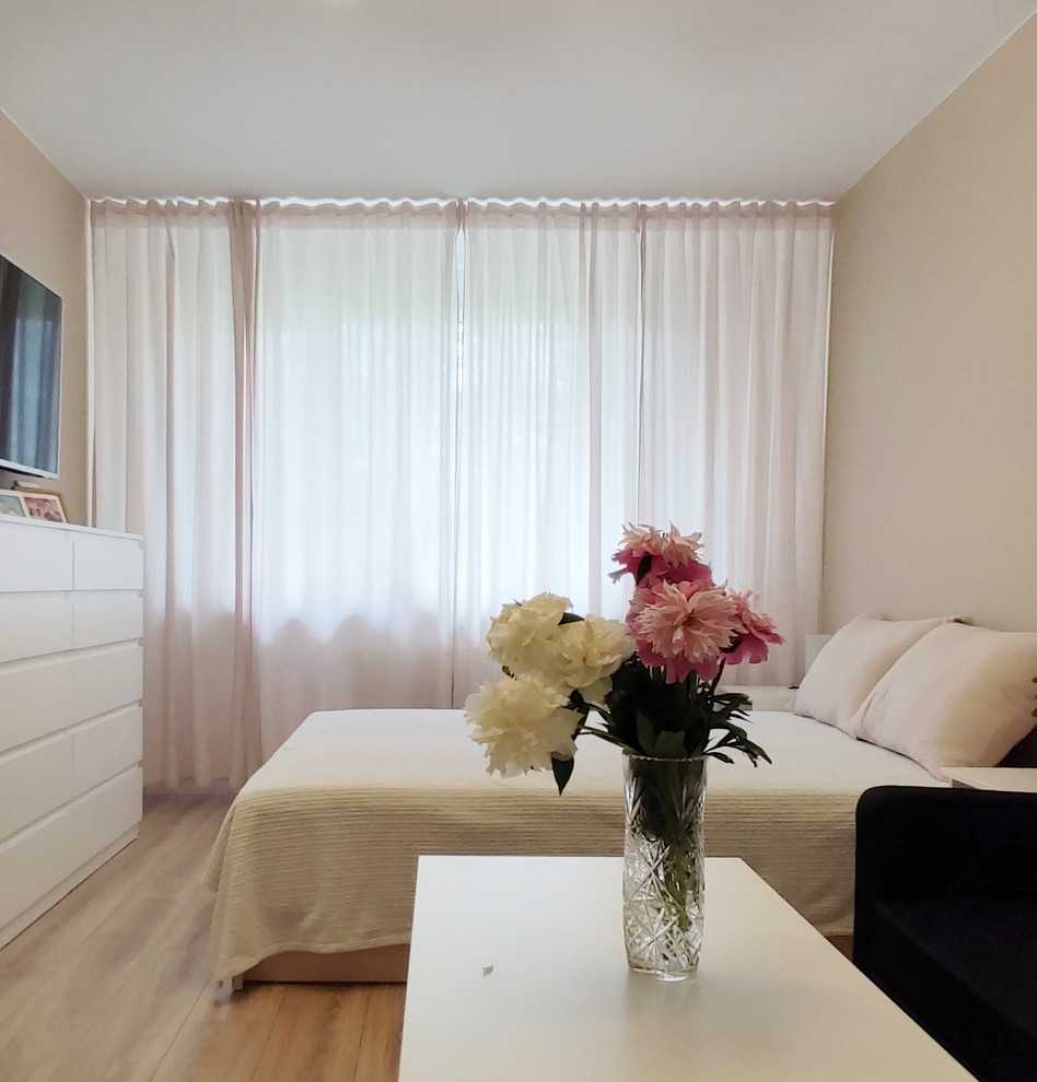 Ejemplo de dormitorio principal actual pequeño sin chimenea con paredes beige, suelo laminado y suelo marrón
