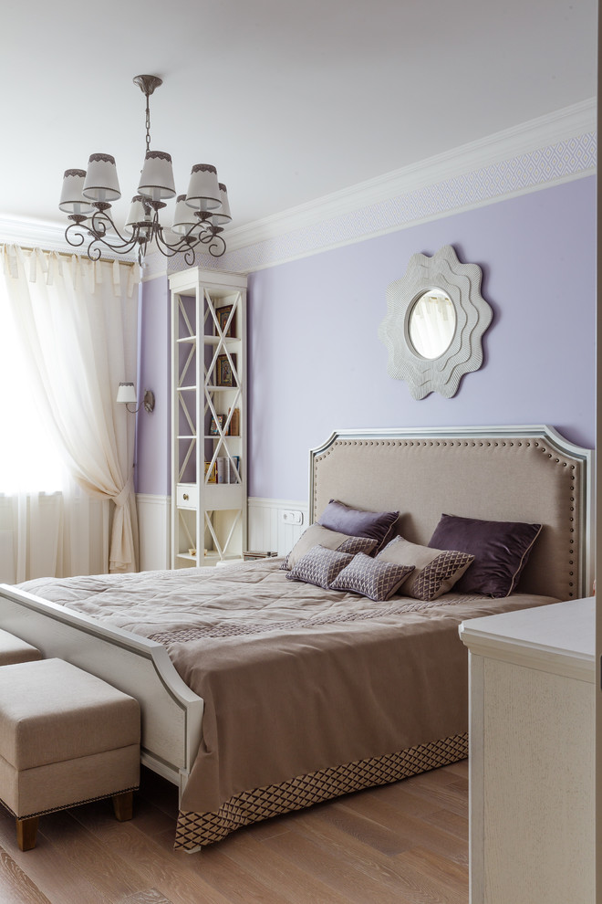 Diseño de dormitorio principal tradicional renovado de tamaño medio sin chimenea con paredes púrpuras, suelo de madera en tonos medios y suelo beige
