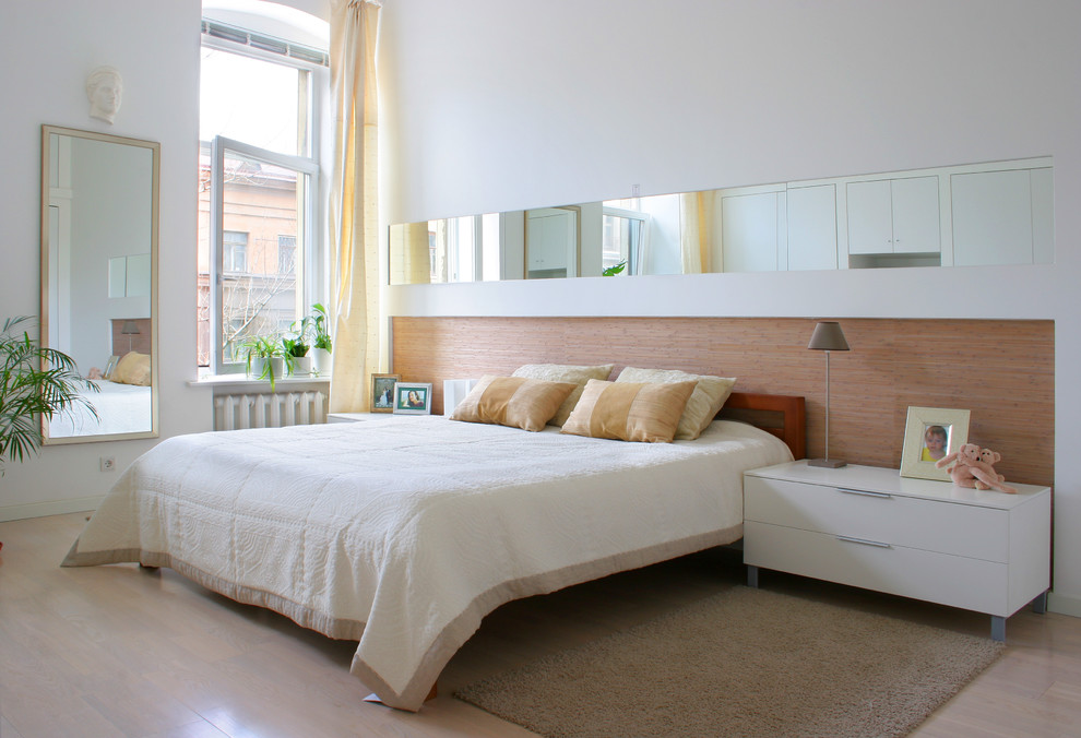 На фото: спальня в современном стиле с светлым паркетным полом и белыми стенами с