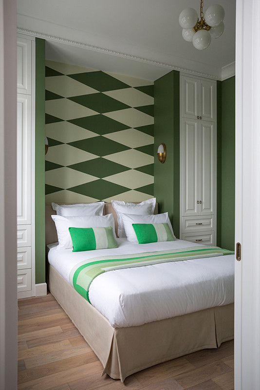 Diseño de dormitorio principal actual de tamaño medio sin chimenea con paredes verdes, suelo de madera en tonos medios y suelo marrón