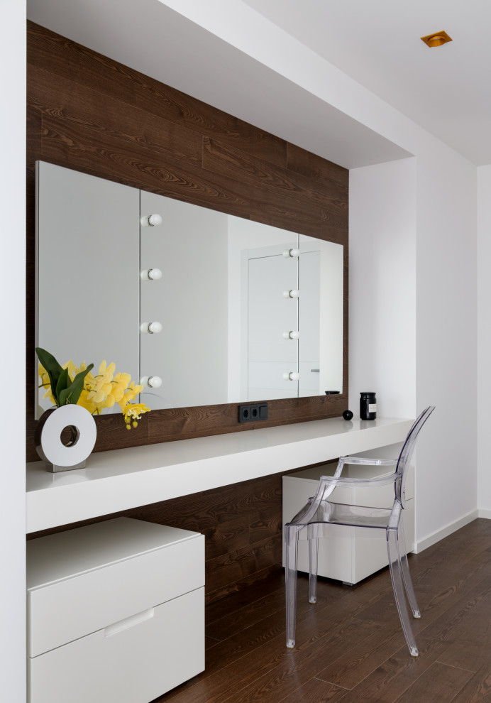 Modelo de dormitorio principal actual de tamaño medio con paredes blancas, suelo de madera en tonos medios, suelo marrón y madera