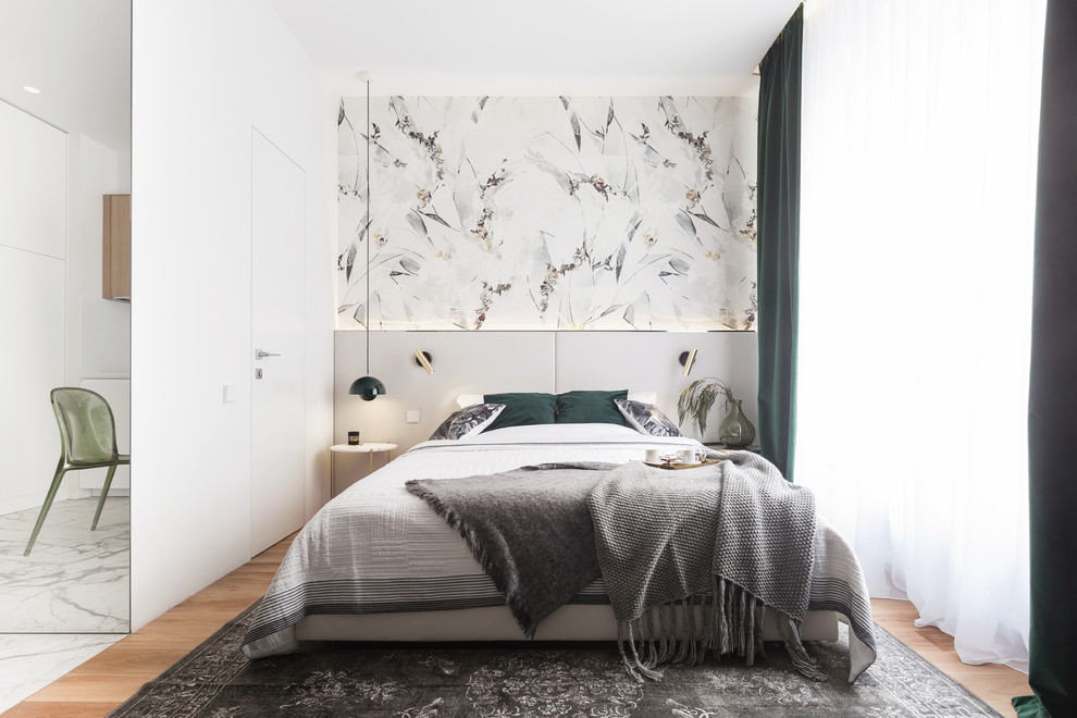 Modelo de dormitorio principal actual con suelo de madera en tonos medios, paredes multicolor y suelo beige