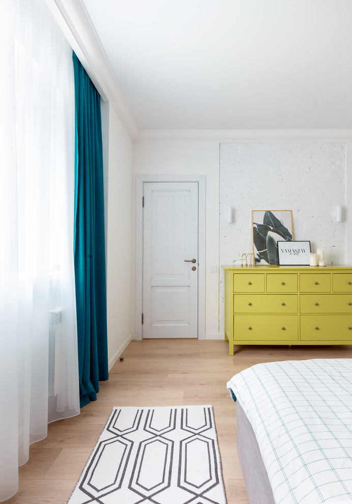 Modelo de dormitorio principal bohemio de tamaño medio con paredes blancas, suelo laminado y suelo beige