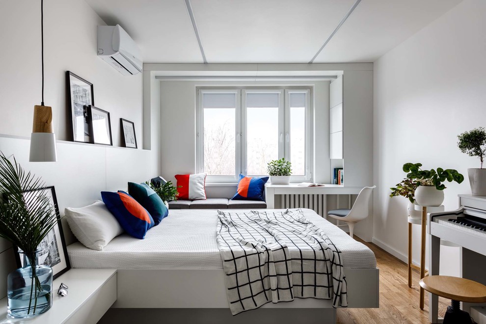 Immagine di una piccola camera matrimoniale design con pareti bianche, pavimento in legno massello medio e pavimento marrone