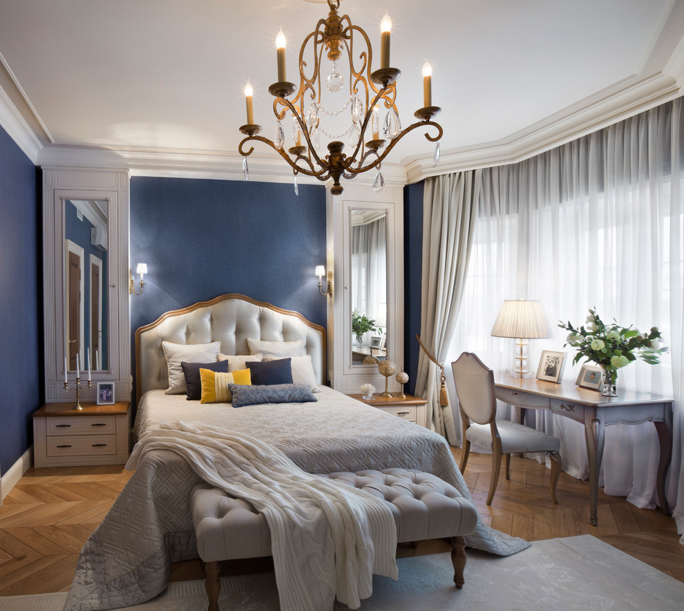 Imagen de dormitorio principal clásico con paredes azules, suelo de madera clara y con escritorio
