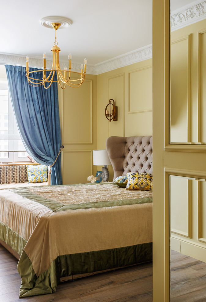 На фото: хозяйская спальня в классическом стиле с желтыми стенами, паркетным полом среднего тона, коричневым полом и синими шторами с