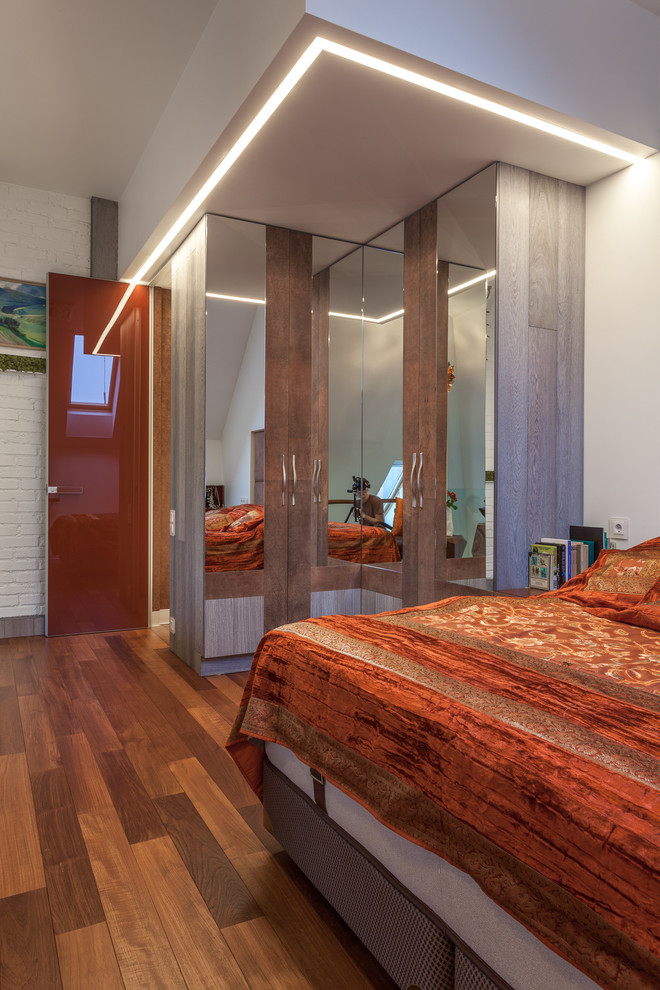 Imagen de dormitorio tipo loft industrial de tamaño medio sin chimenea con paredes blancas, suelo de madera oscura y suelo marrón
