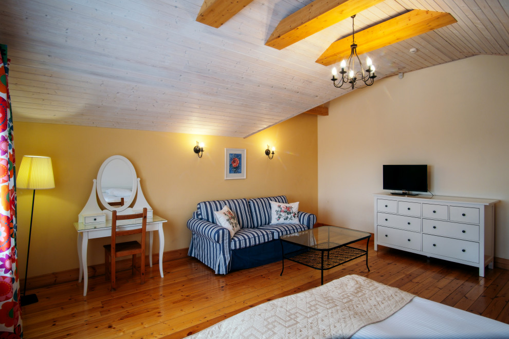 Immagine di una camera degli ospiti industriale con pareti gialle, pavimento in legno verniciato e nessun camino