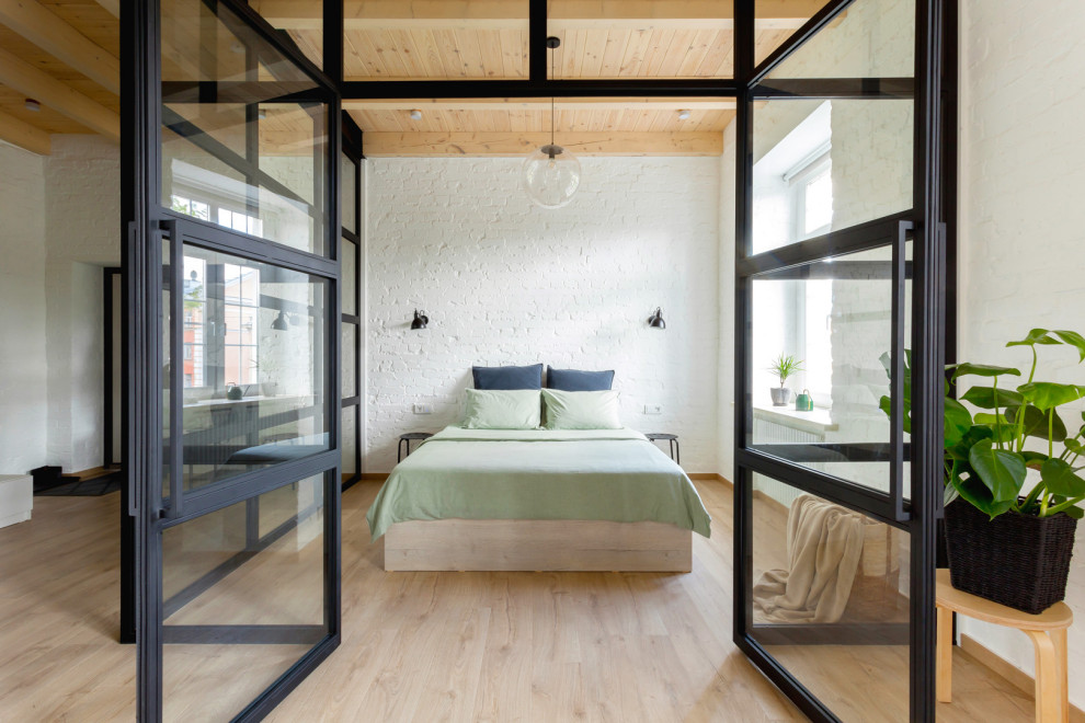 Modelo de dormitorio urbano con paredes blancas, suelo de madera clara, suelo beige, madera y ladrillo