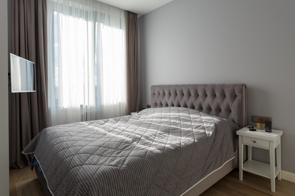 Modelo de dormitorio principal escandinavo pequeño con paredes grises, suelo de madera en tonos medios y suelo beige