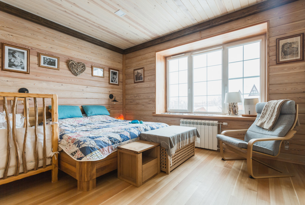 Modelo de dormitorio principal campestre con paredes marrones y suelo de madera clara