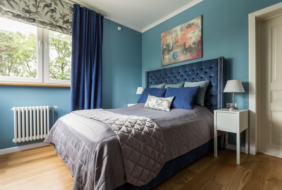 Imagen de dormitorio principal actual con paredes azules, suelo de madera en tonos medios y suelo marrón