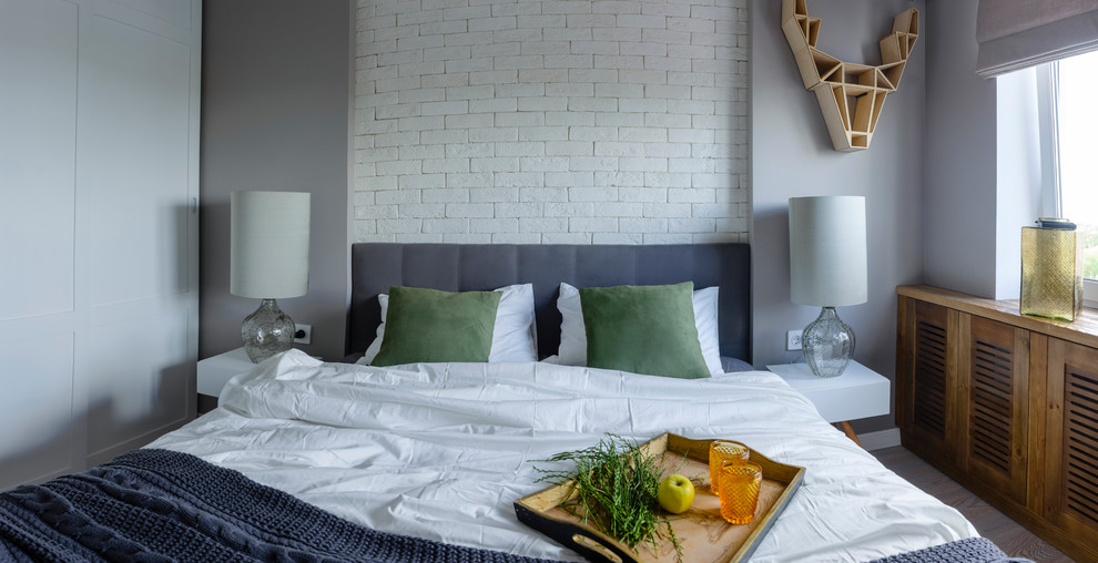 Ejemplo de dormitorio principal escandinavo pequeño sin chimenea con paredes grises y suelo de madera clara