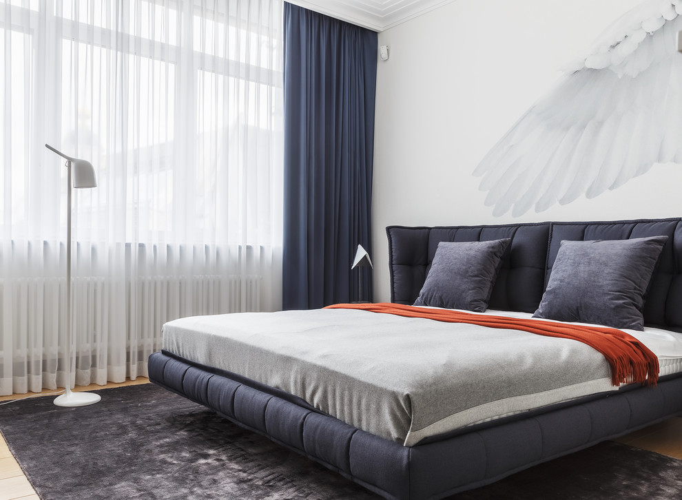 Ejemplo de dormitorio principal actual con paredes blancas, suelo de madera en tonos medios y suelo gris