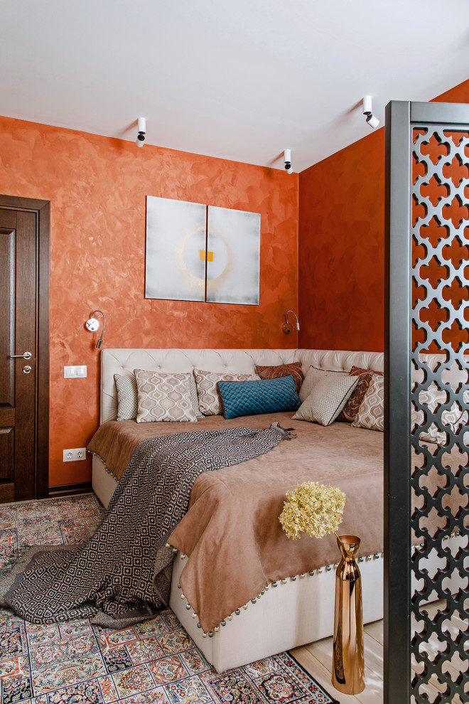 World-inspired master bedroom in Other with orange walls, light hardwood flooring and beige floors.