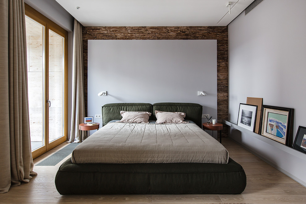 Cette photo montre une chambre parentale tendance avec un mur blanc, parquet clair et un sol beige.