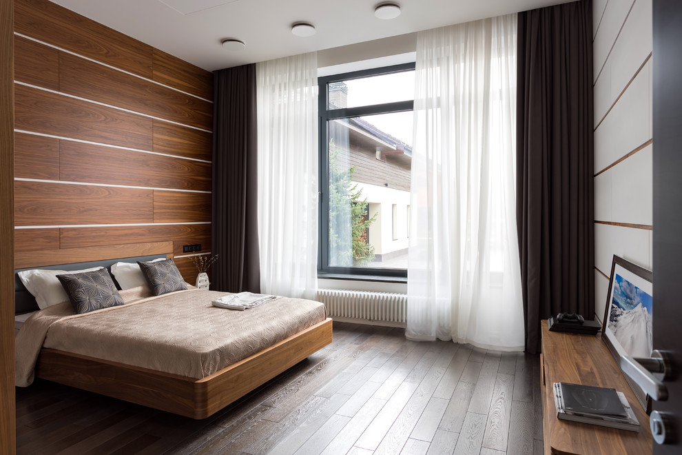 Cette image montre une chambre design avec un mur blanc, parquet foncé et un sol marron.