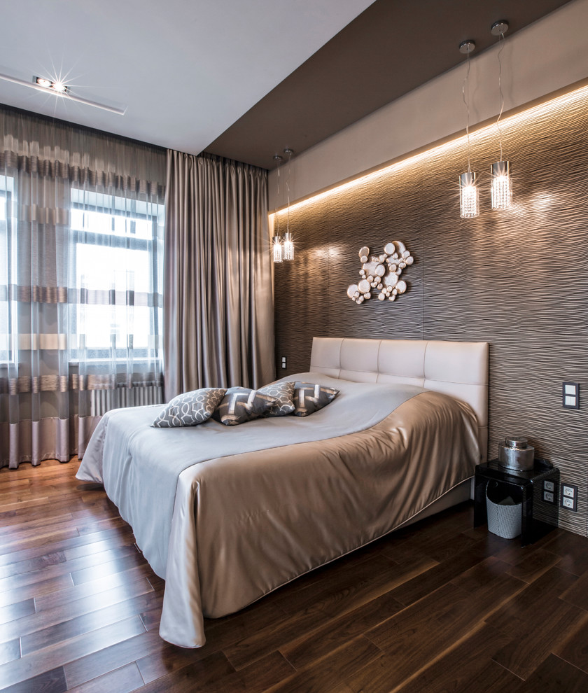 Diseño de dormitorio principal actual grande sin chimenea con paredes beige, suelo de madera en tonos medios y suelo marrón