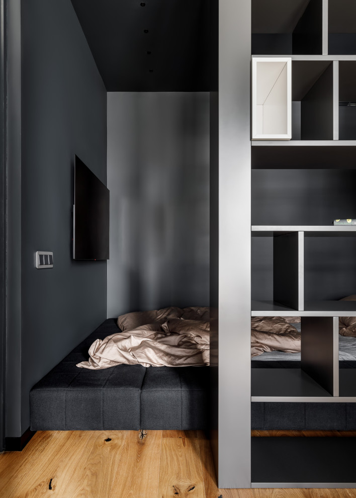 На фото: хозяйская спальня в современном стиле с черными стенами, паркетным полом среднего тона, коричневым полом, телевизором и кроватью в нише