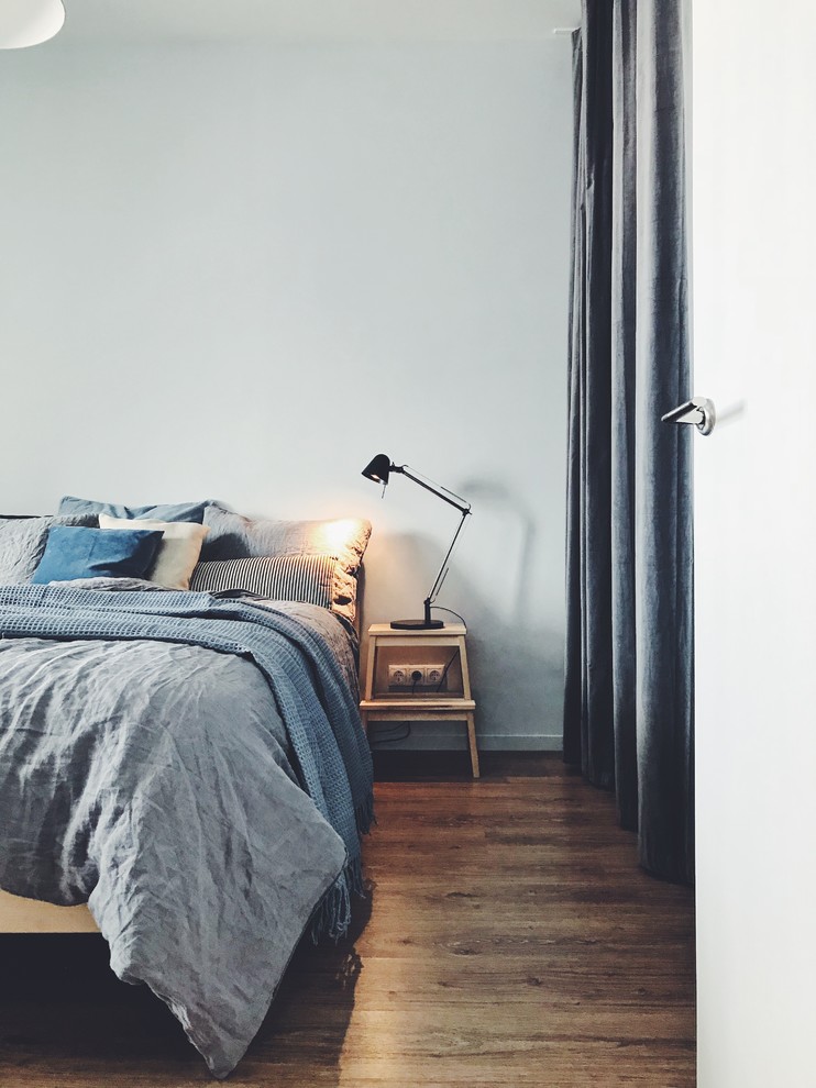 Diseño de dormitorio principal nórdico de tamaño medio con paredes grises, suelo laminado y suelo marrón