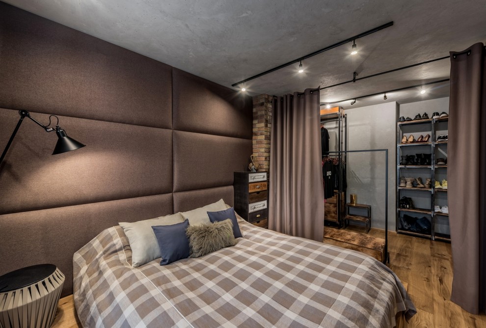 Foto de dormitorio principal urbano con paredes marrones, suelo de madera en tonos medios y suelo marrón