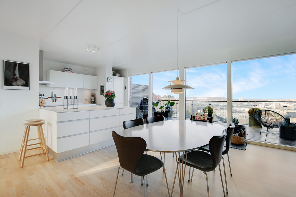 Cette image montre une salle à manger ouverte sur la cuisine nordique avec un sol beige, un mur blanc et parquet clair.